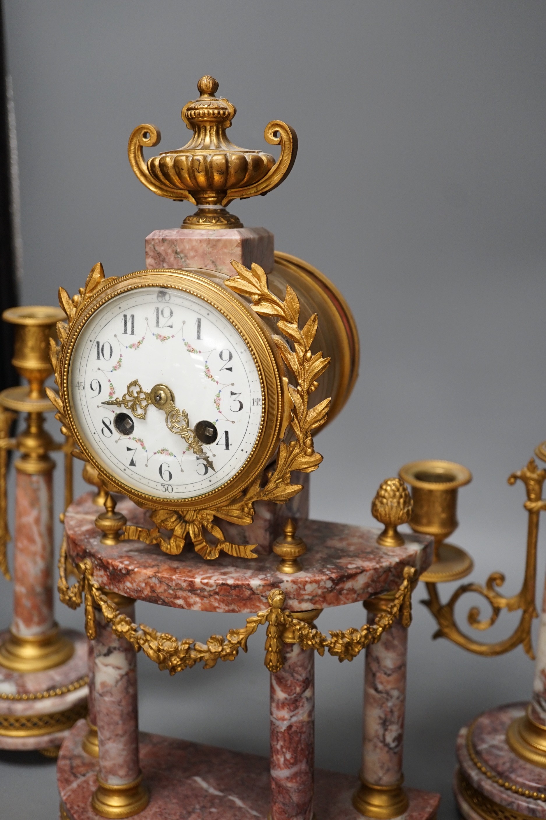 A French ormulu and rouge marble clock garniture, c.1900, with decorative enamel dial, 40cms high.